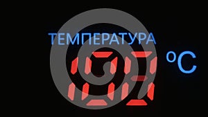 Digital thermometer with red digits shows the temperature rise in celsius against black background. Inscription in the