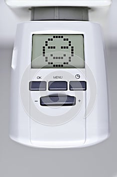 Digital thermostat of an heating radiator with smiley face. Heat and energy concept.