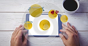 Digitally generated image of various emojis flying over hand using digital tablet at wooden table