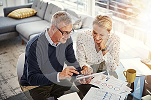 Digitizing the budgeting process. a mature couple using a digital tablet while going through paperwork at home.