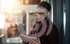 Digitizing business tasks. a young businessman using a digital tablet in a modern office.