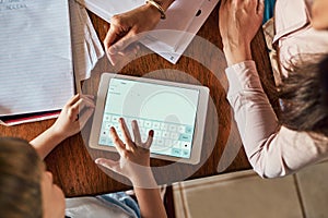 Digitizing his homework. High angle shot of a little boy using a digital tablet while doing homework with help from his