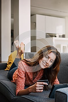 Digitizing the shopping experience. an attractive young woman using a digital tablet and credit card on the sofa at home