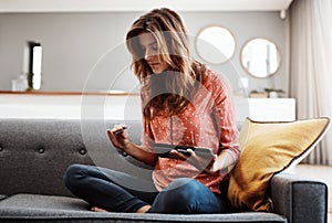 Digitizing the way she shops. an attractive young woman using a digital tablet and credit card on the sofa at home.