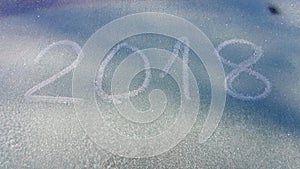 Digits 2018 written on a frozen windshield