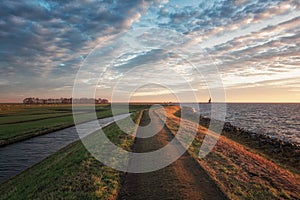 The dike around the island of Marken during sunrise with the lighthouse Het Paard van Marken in the background