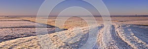 Dike through Dutch landscape in winter at sunrise