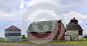 A Dilapidated Old Red Barn, Oval Corn Crib, And Out Buildings