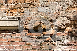 Dilapidated with potholes old brick wall of the building, made of red brick, close up. Background or texture