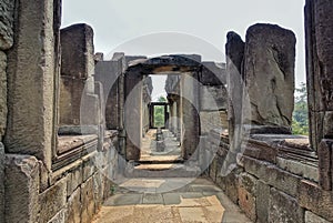 A dilapidated stone corridor at the top of the temple. Doorways, windows, columns are damaged by time.