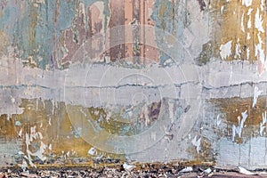 Dilapidated wall of a room with layers of paint, pieces of wallpaper