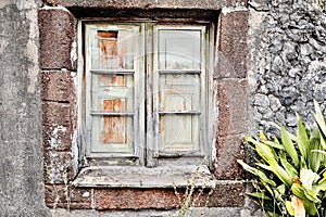 A dilapidated wooden window in an old stone house on Madeira, Portugal.