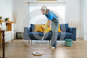 Diligent Asian housewife meticulously mops the living room, epitomizing dedication and determination in maintaining a clean and