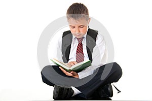 A diligent boy reads a book and prepares for exams and tests. Schoolboy teenager dressed in a school uniform. Isolated white