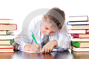 A diligent high school student boy sits in a library with books and learns lessons, writes homework. Exam preparation, testing