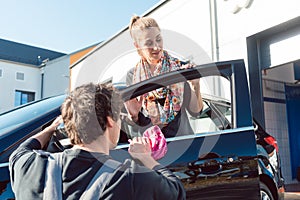 Diligent service man helping woman cleaning her car in commercial wash