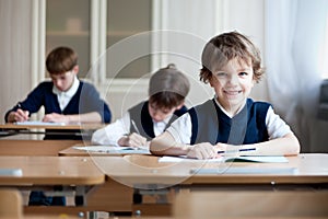 Diligent student sitting at desk, classroom photo