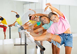 Diligent tween girl practicing classic dance moves near ballet barre