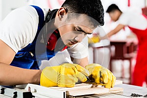 Diligent worker in factory working on wood