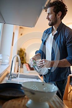 A diligent young man doing housework in the kitchen. Kitchen, housework, quarantin, home