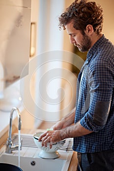 A diligent young man washing dishes in the kitchen. Kitchen, housework, quarantin, home