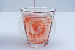 Diluted fruit juice poured into glass of water