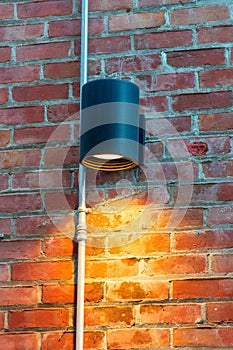 Mate la luz negro alojamiento sobre el ladrillo muro delgado gris verticalmente tubo en urbano Área de la ciudad 