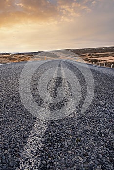 Diminishing empty road amidst landscape in volcanic valley against sky during sunset