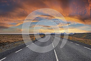 Diminishing empty road amidst volcanic landscape against cloudy sky during sunset