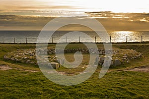 Dinas Dinlle excavated remains of an Iron Age house with the sun setting over the Irish sea. Dinas Dinlle is on the North Wale photo