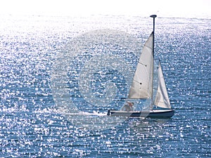 Dinghy sailing on silvery sea