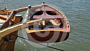 Dinghy, small rowing boat, made of mahogany wood, attached to the stern of a vintage sailing yacht. Schleswig-Holstein, Germany