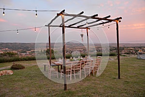 Dining outdoor in the Italian countryside. Decked table al fresco by sunset