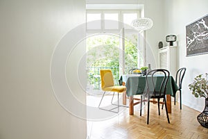 Dining room interior with wooden furniture,white walls, copy space and wide open glass door to balcony