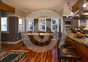 Dining room and kitchen breakfast bar with wood floors and granite countertops in contemporary upscale home interior