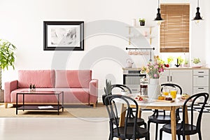 Dining table with breakfast and fresh flowers standing in bright