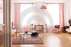Dining table with chair in the middle of bright pastel pink living room in tenement house