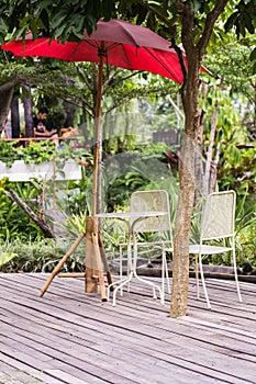 Dining table with chairs and red parasol in garden