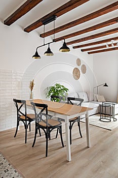 Dining table with chairs under metal luster in apartment