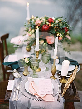 Dining table with floral decoration and festive table setting idea outdoor, closeup details on the beach