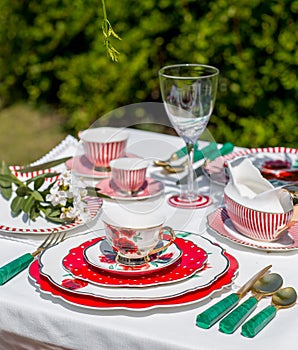 Dining table placed in the outdoors and it's beautifully decorated with plates, cups, and candles