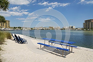 Dining table with seats and lounge chairs on a white sand shore at Destin, Florida bay