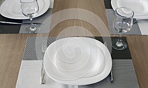 Dining table served with plates, glasses, forks and knives