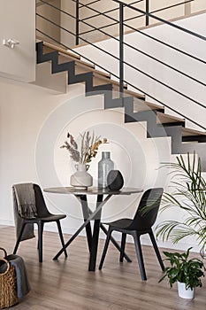 Dining table with two chairs next to stairs