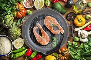 Dinner cooking ingredints. Raw uncooked salmon fish with vegetables, rice, herbs, spices and oil in iron grilling pan