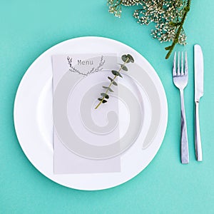 Dinner menu for a wedding or luxury evening meal. Table setting from above. Elegant empty plate, cutlery and flowers.