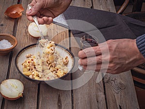 Dinner pasta with meat. The hands of a man hold a spoon with food and a glass with red wine