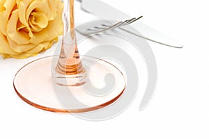 Dinner place setting. Knife and fork and glass with yellow rose