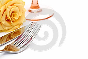 Dinner place setting. Knife and fork and glass with yellow rose