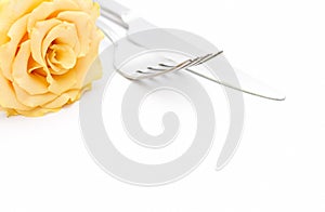 Dinner place setting. Knife and fork with yellow rose